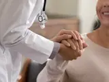 Medisch specialist houdt hand vast van een blije patiënt. 
